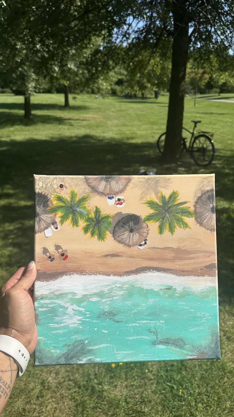 Painted canvas of a beach scene held outdoors