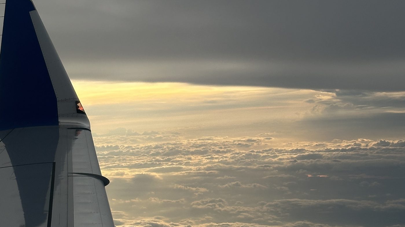 Aircraft wing above a layer of cloud at dusk